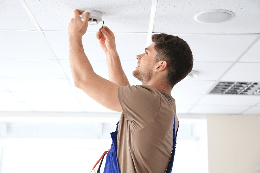 Technician installing or repairing ceiling equipment.
