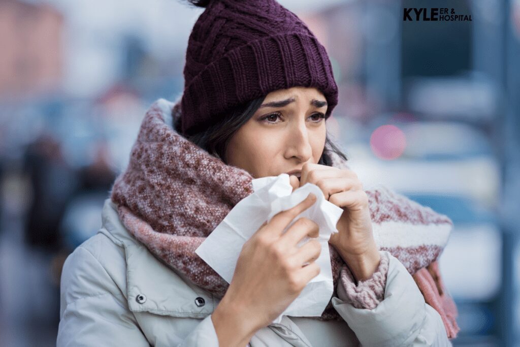 A woman with a cold blows her nose into a tissue outdoors.