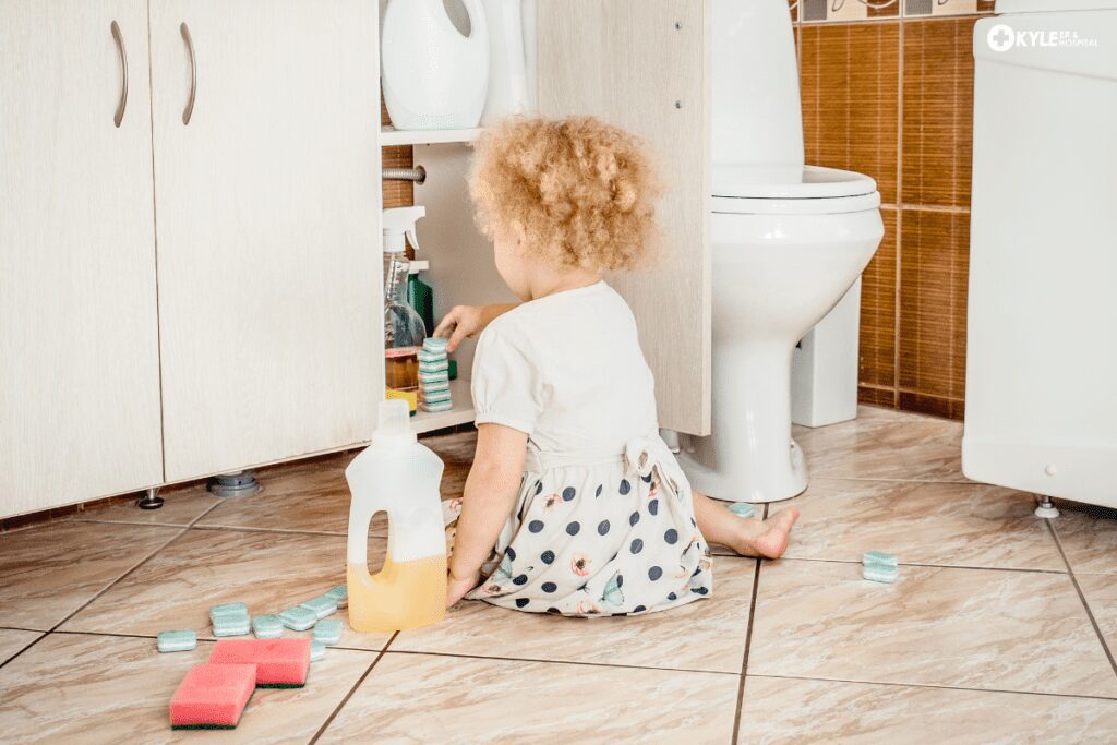 A toddler playing with cleaning supplies in a bathroom.