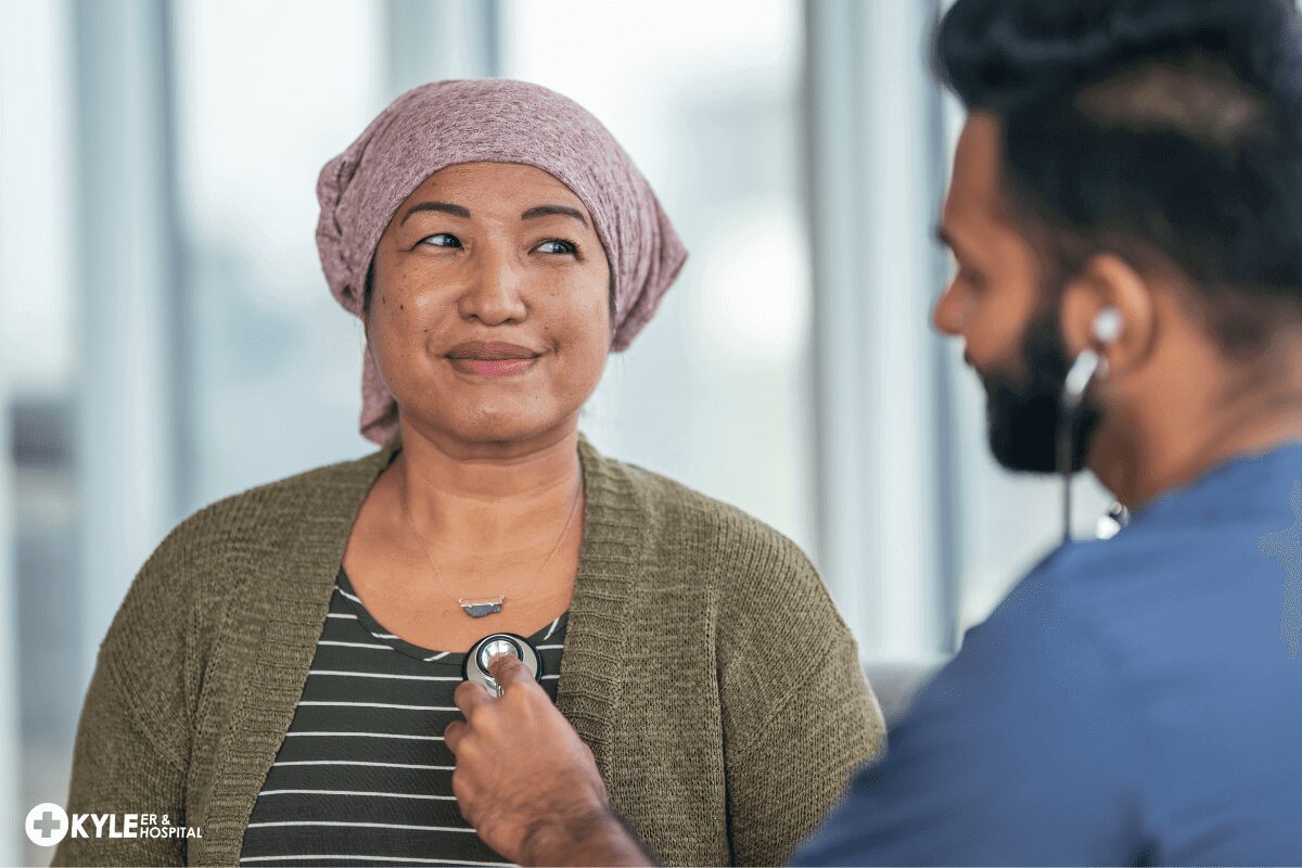 A doctor using a stethoscope to examine a smiling woman wearing a headscarf.