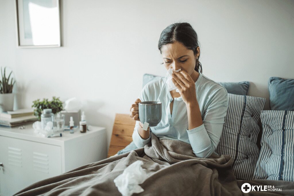 Woman sitting in bed, holding a mug and blowing her nose.